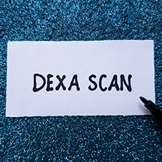 Cartonaș cu textul „DEXA SCAN”, reprezentând investigația DEXA utilizată pentru evaluarea densității osoase și a compoziției corporale.