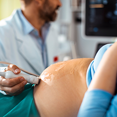 Medic efectuând o ecografie unei femei însărcinate